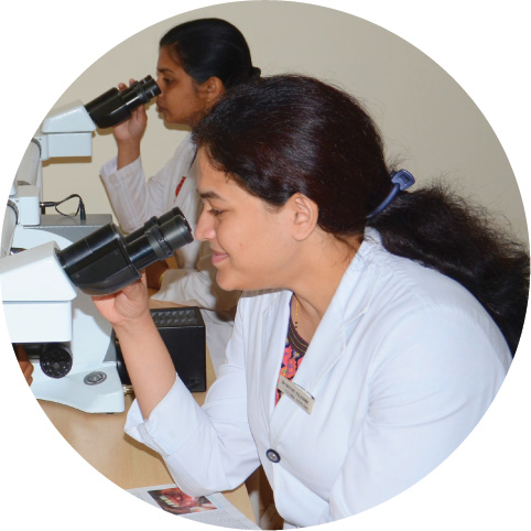 Two female researchers looking into their microscopes