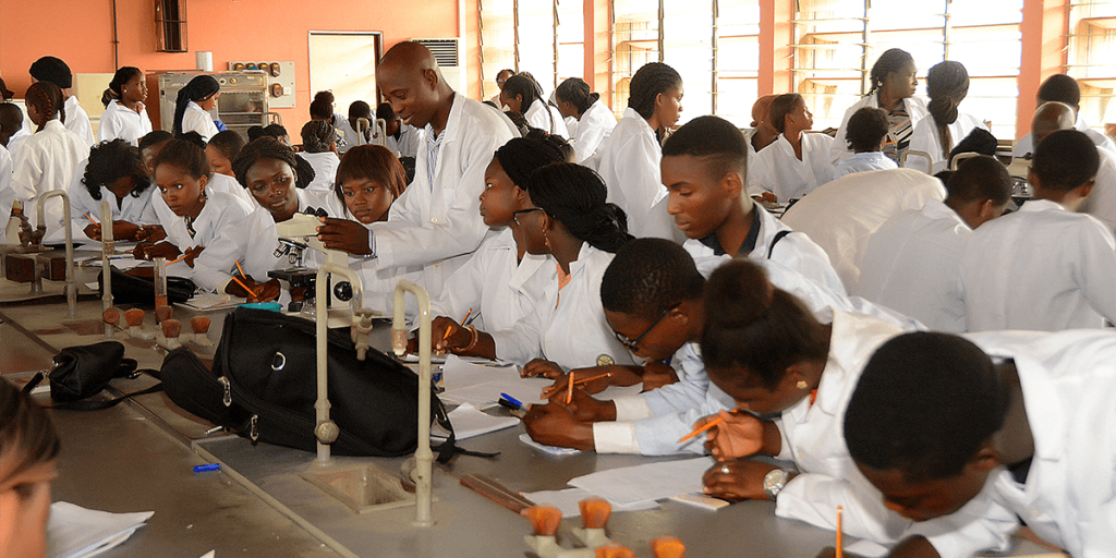 Dr. M.O. Sifau demsonstrating the use of a microscope to students at a laboratory session